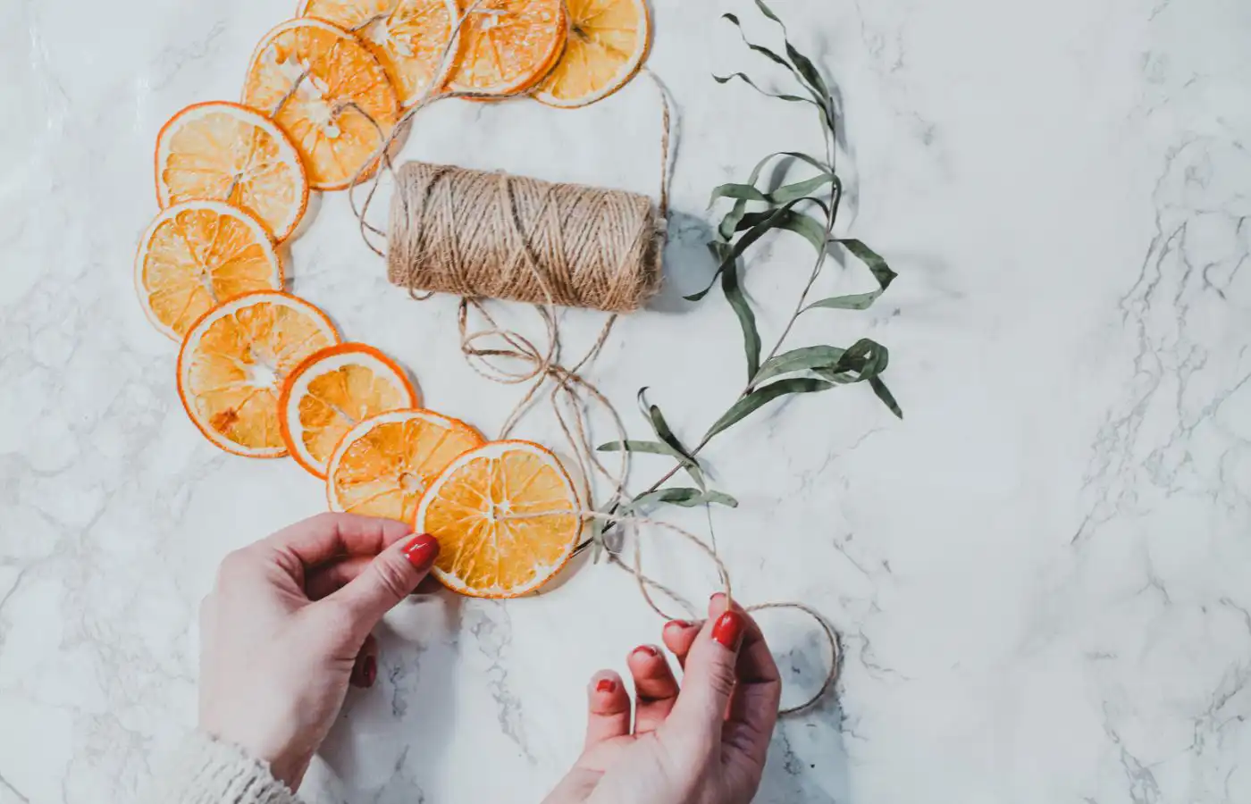 DIY guirlande de Noël avec des tranches d'orange séchées et de la ficelle en jute pour une décoration naturelle et parfumée.