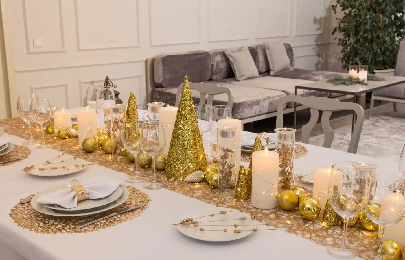 Table de Noël décorée dans des tons dorés avec des bougies, des guirlandes lumineuses et des éléments naturels, créant une ambiance festive et élégante.